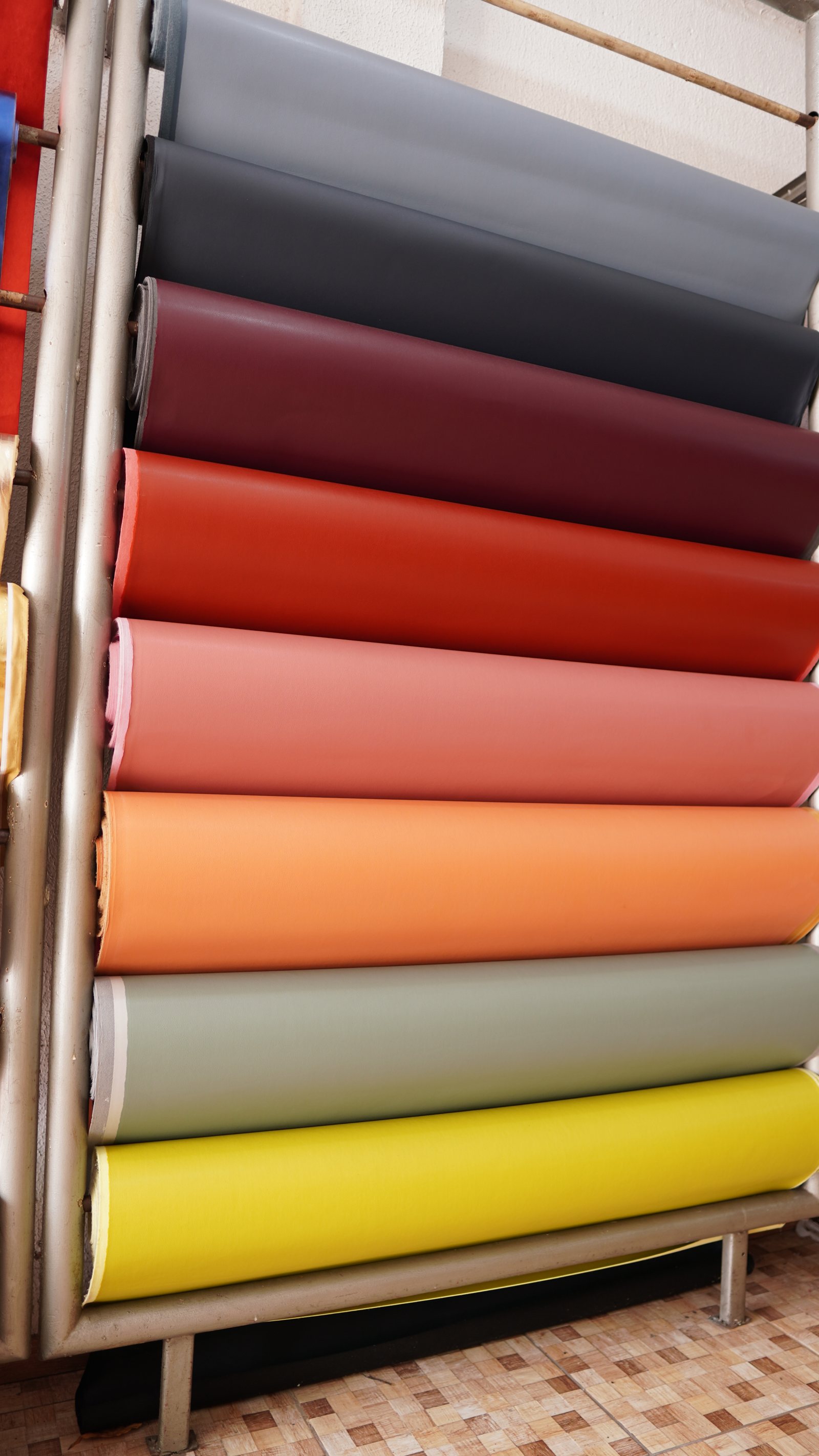 Estante da Fortal Couros com rolos de sintético coloridos